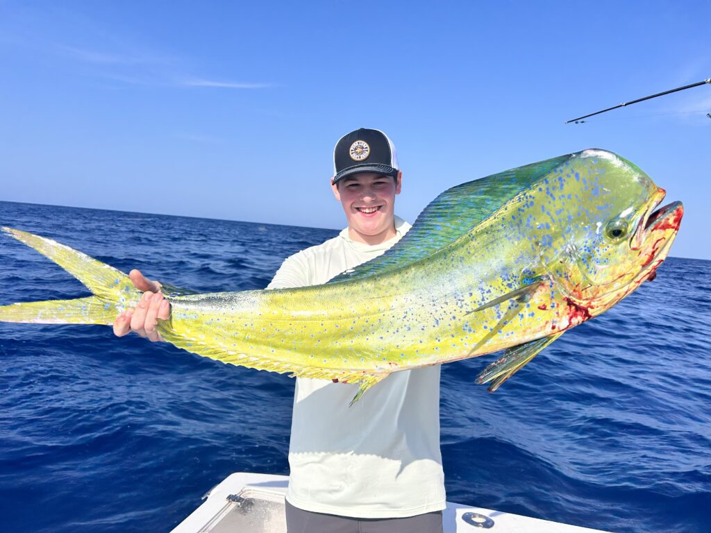 a young man shows off a large bull mahi that he caught while aboard Rock Bottom with SeaCo Fishing Charters in St. Augustine, Florida