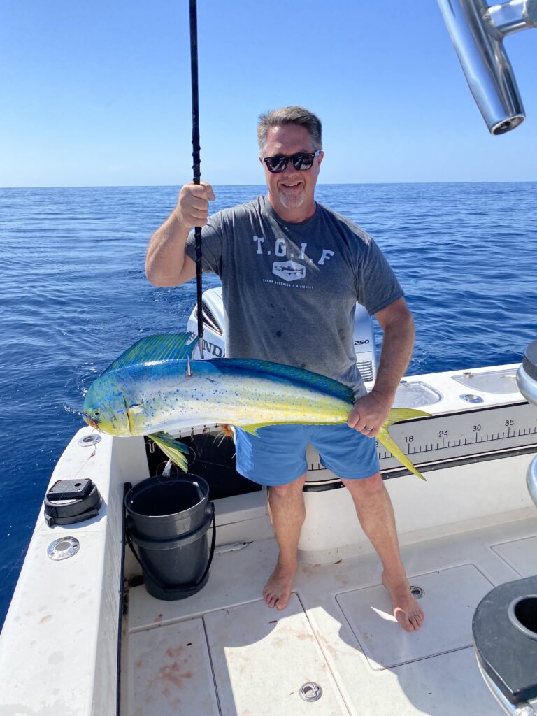 Charter guest showing off his freshly caught, beautifully lit up, mahi-mahi in blue, white and yellow, while mahi fishing in St. Augustine, fl with SeaCo Fishing Charters
