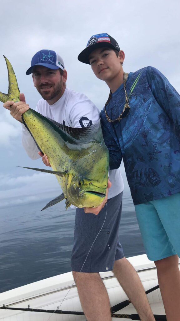 Captain Ricky Poupore with son, Hunter Poupore, showing off a nice bull dolphin caught offshore mahi fishing - SeaCo Fishing Charters