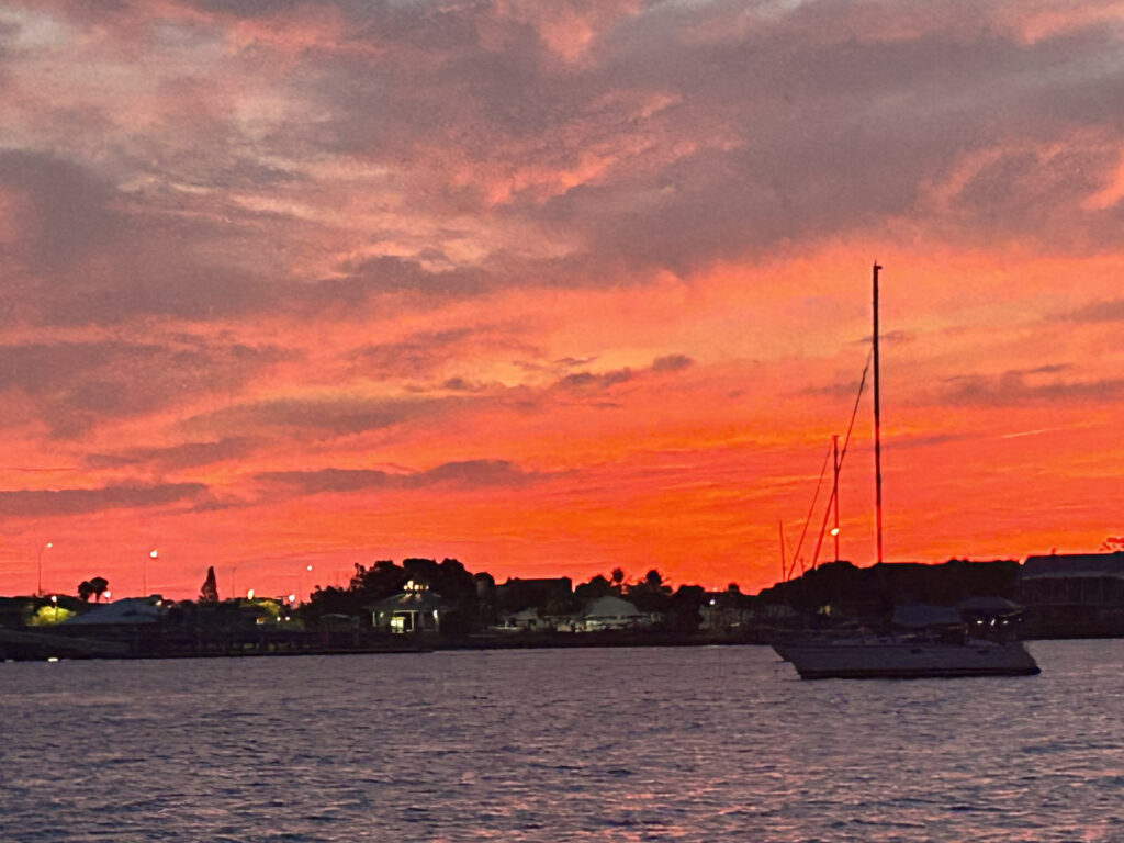 Bright Bold orange red sunset photo with silhouette of sailboat in St. Augustine taken from SeaCo Fishing Charters boat.